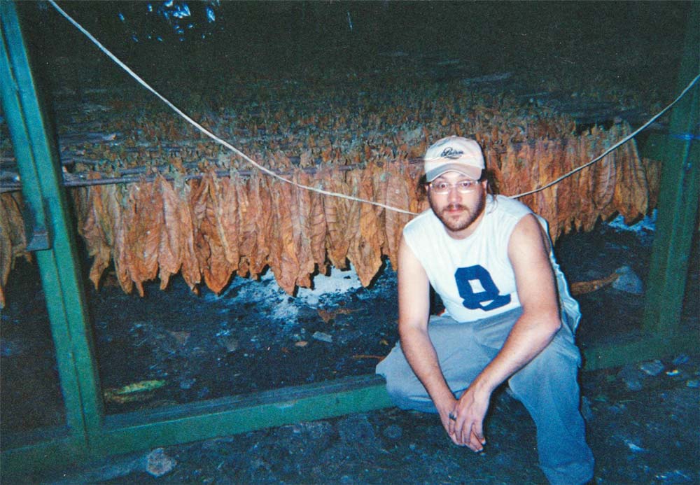 Jonathan shows off tobacco in a curing barn.